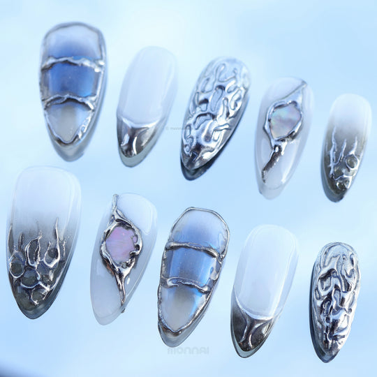 Metal Blaze press-on nails laid out in a cool modern design with grey tones, chrome edges, sculpted accents, and iridescent inlays