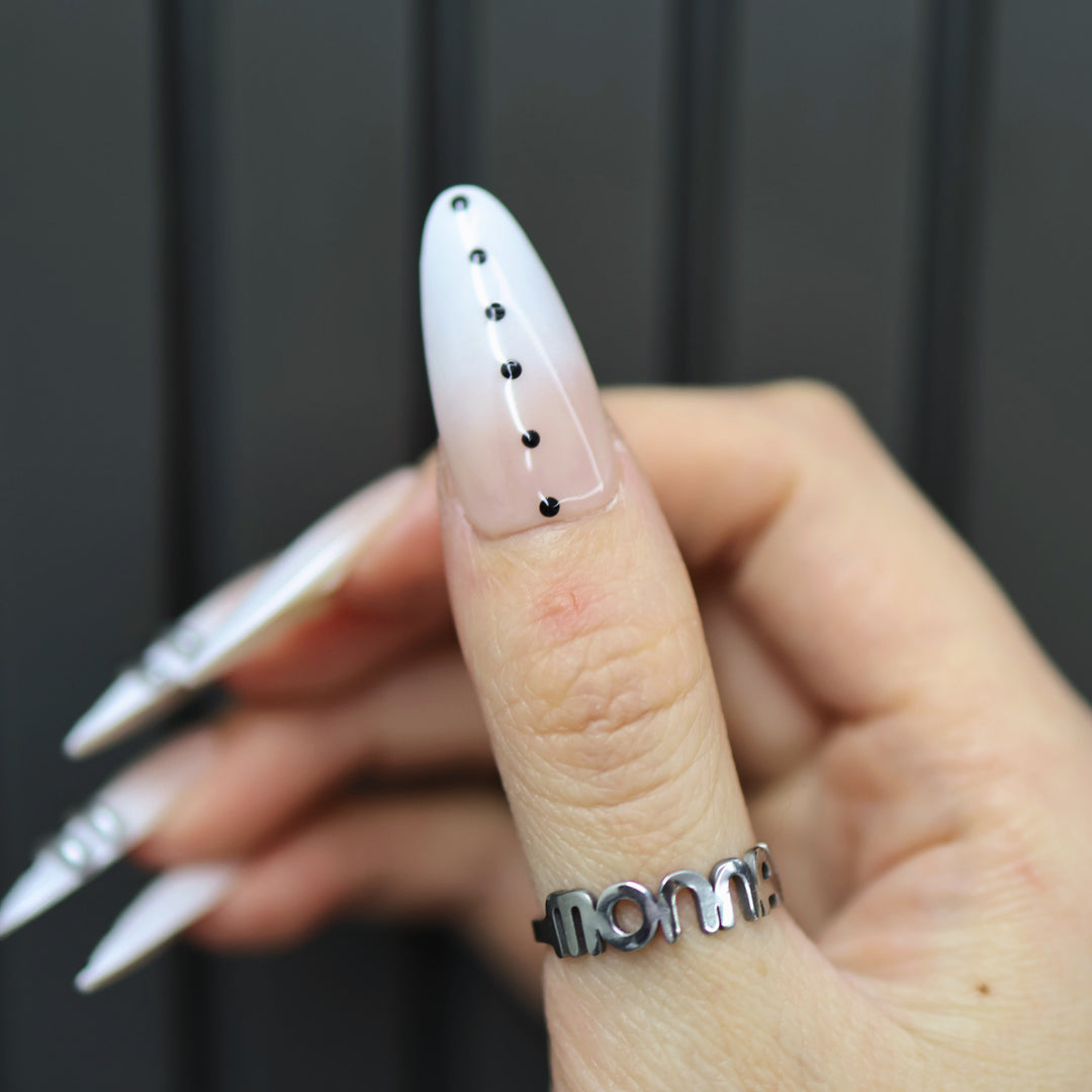 Metal Dot press-on nails on-hand view: sheer nude stiletto nail with black dots and silver chrome lines
