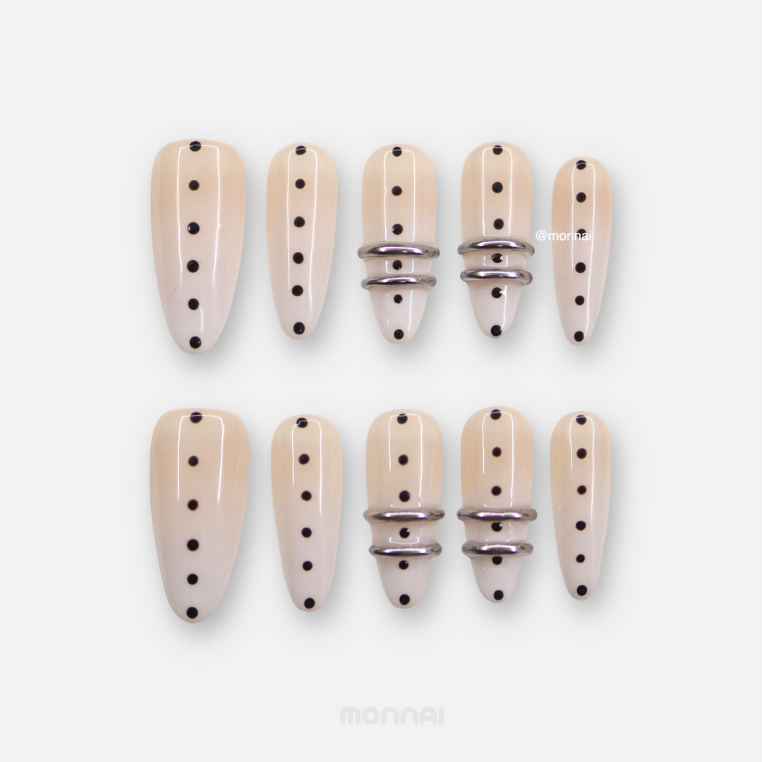 Metal Dot press-on nails laid out in nude with black polka dots and silver chrome rings