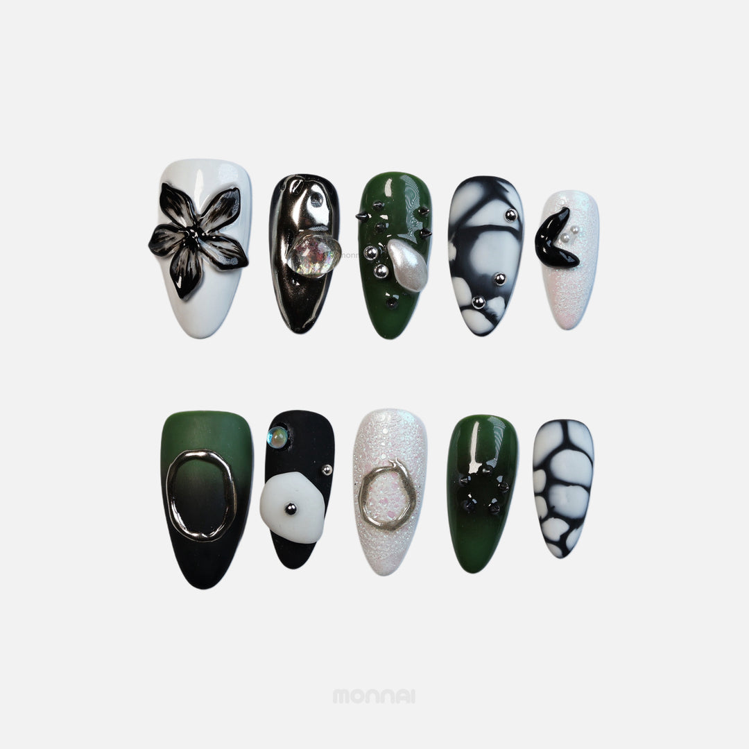 Metallic Mist press-on nails laid out in avant-garde black, green and white sculptural designs with metallic accents.