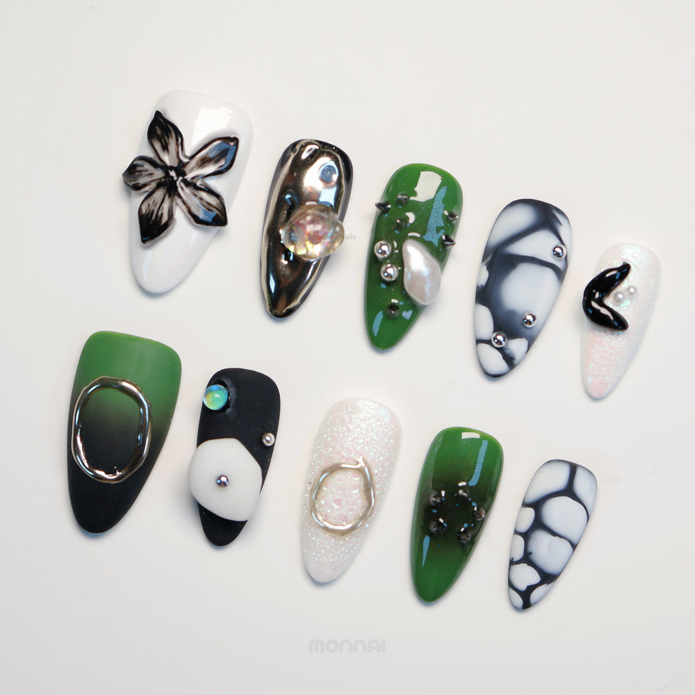 Metallic Mist press-on nails laid out with deep olive green, monochrome accents, glossy finishes, and metallic sculpted details
