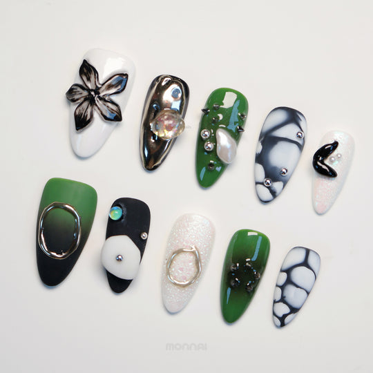 Metallic Mist press-on nails laid out with deep olive green, monochrome accents, glossy finishes, and metallic sculpted details