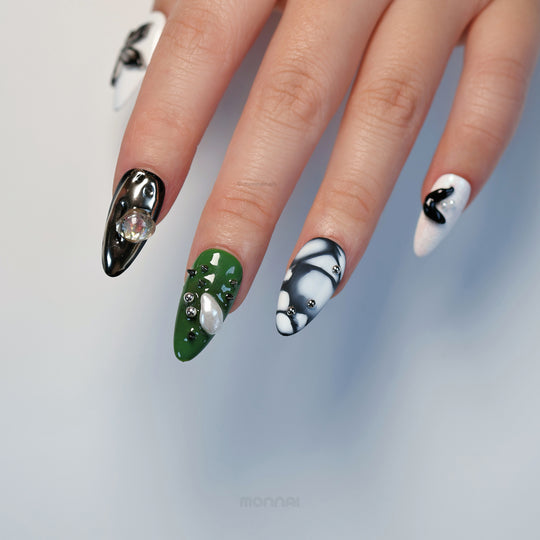Metallic Mist press-on nails on hand, showing sculptural olive green and monochrome designs with metallic accents