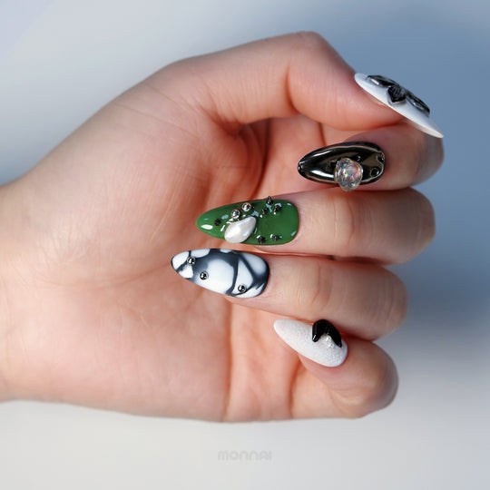 Metallic Mist press-on nails on hand, showcasing avant-garde olive green, black, and white sculptural details with metallic accents