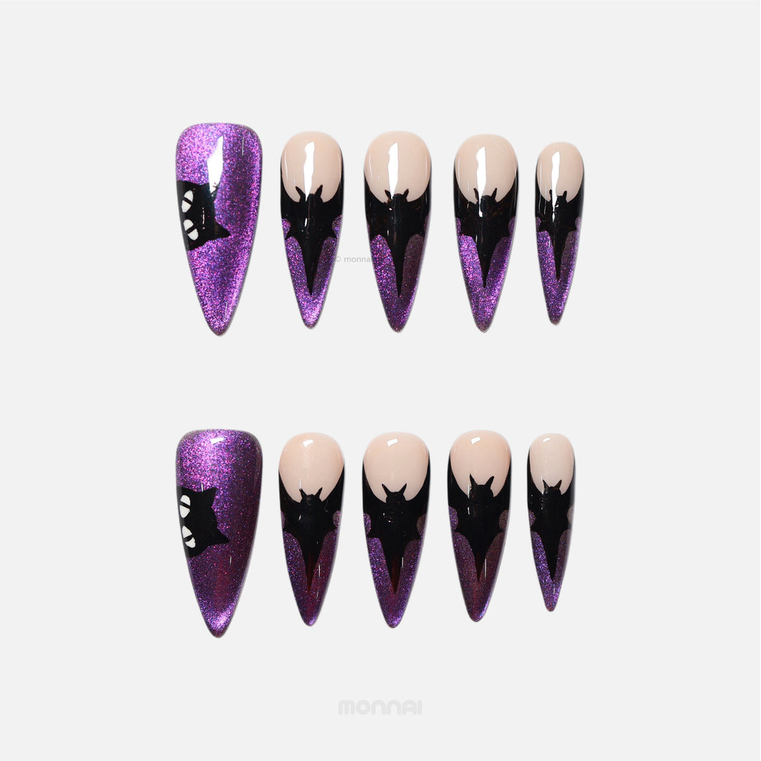 Midnight Bat press-on nails laid out, showing purple cat-eye shimmer, nude base, and black bat silhouettes.