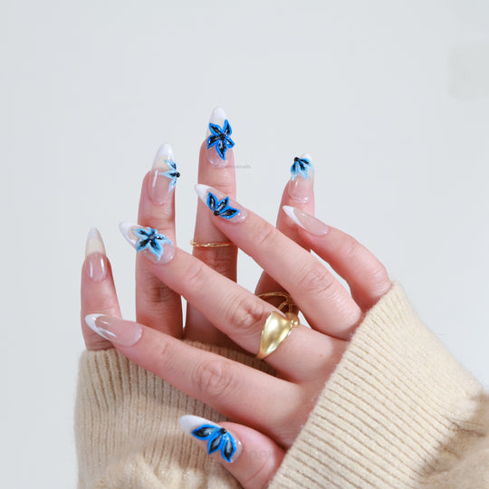 Midnight Petals press on nails with electric blue 3D floral design over milky white French tips.