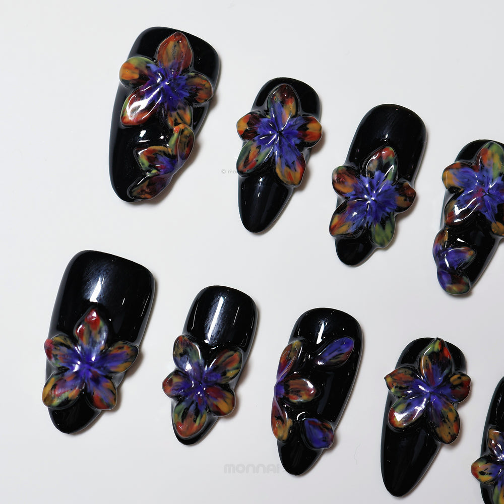 Midnight Violet press-on nails laid out, black with glossy 3D floral blooms in purple and multicolor tones.