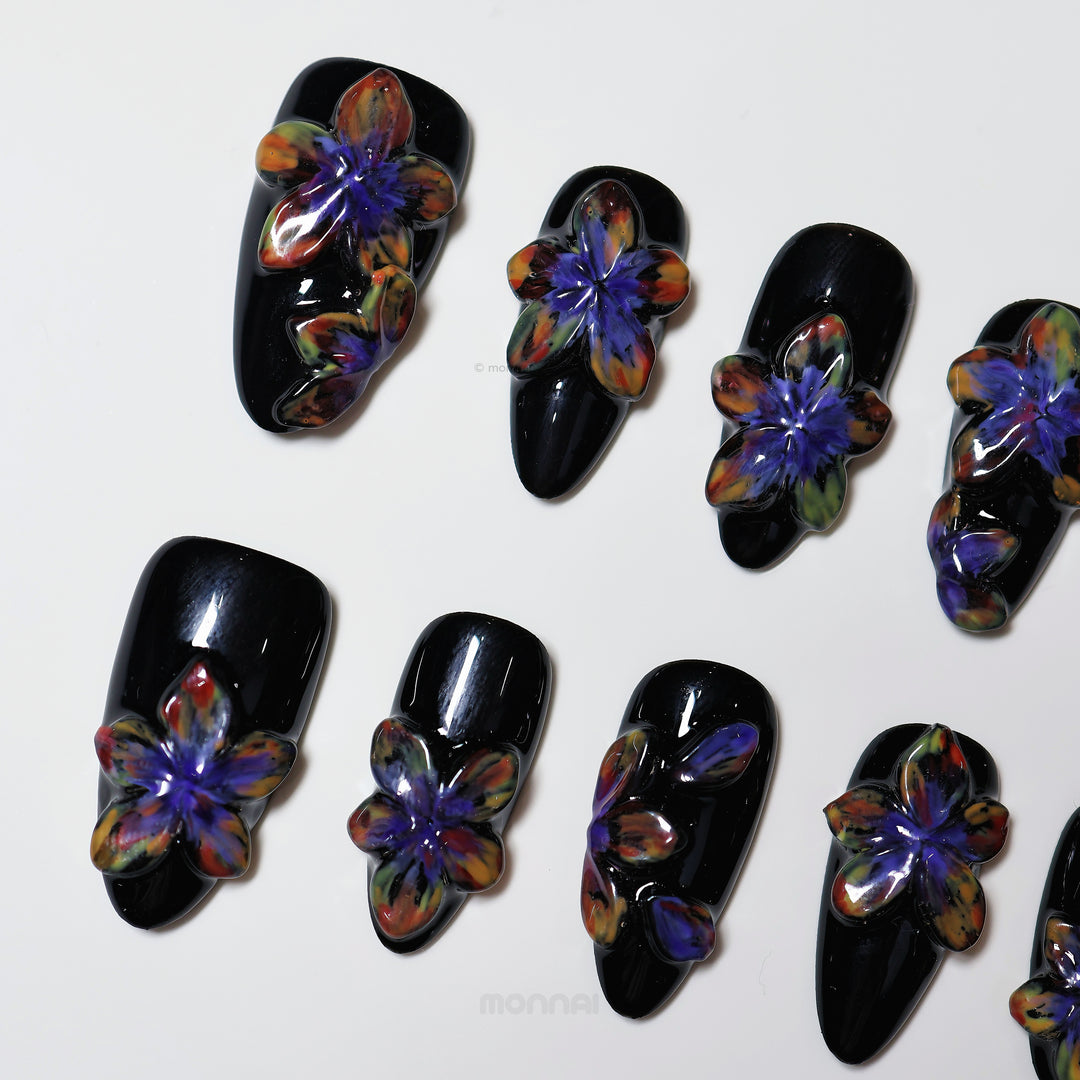 Midnight Violet press-on nails laid out, black with glossy 3D floral blooms in purple and multicolor tones.