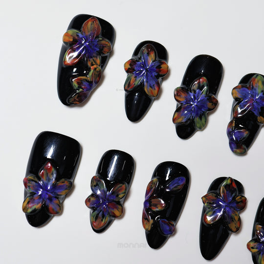 Midnight Violet press-on nails laid out, black with glossy 3D floral blooms in purple and multicolor tones.