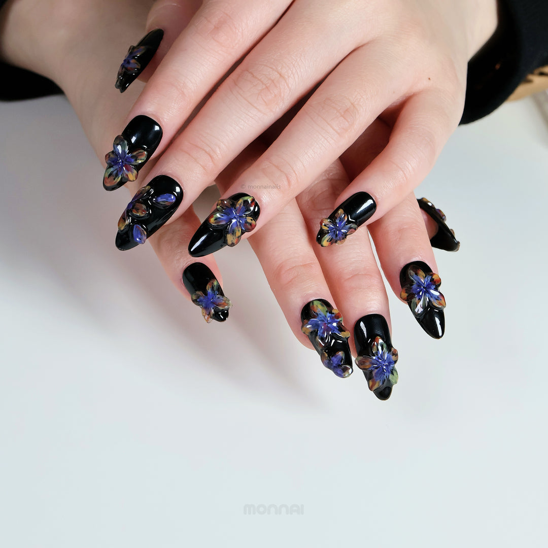 Midnight Violet press-on nails worn on hands, glossy black base with sculpted 3D floral accents.