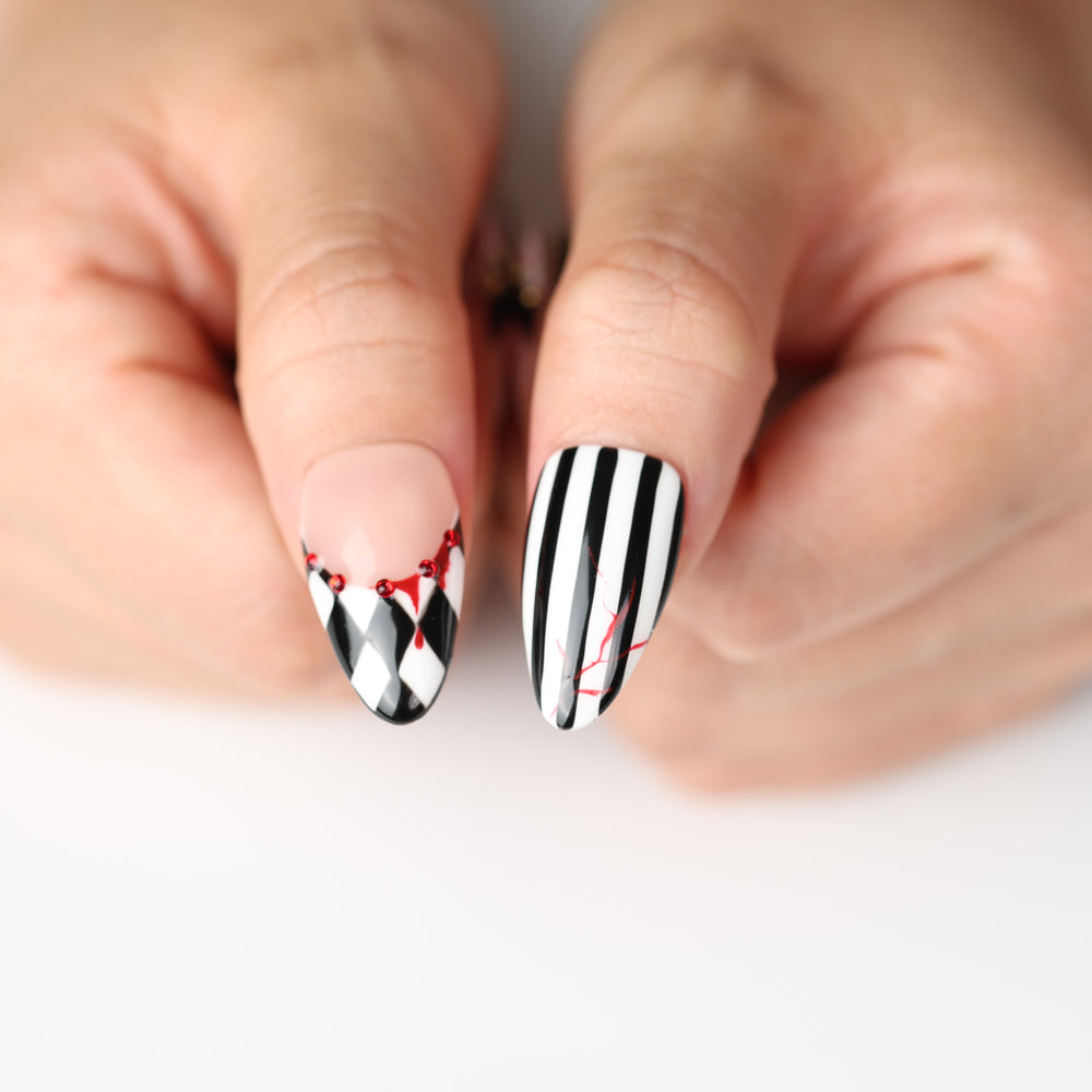 Midnight Marionette press on nails with black-and-white harlequin stripes, red drips, and gothic Halloween flair