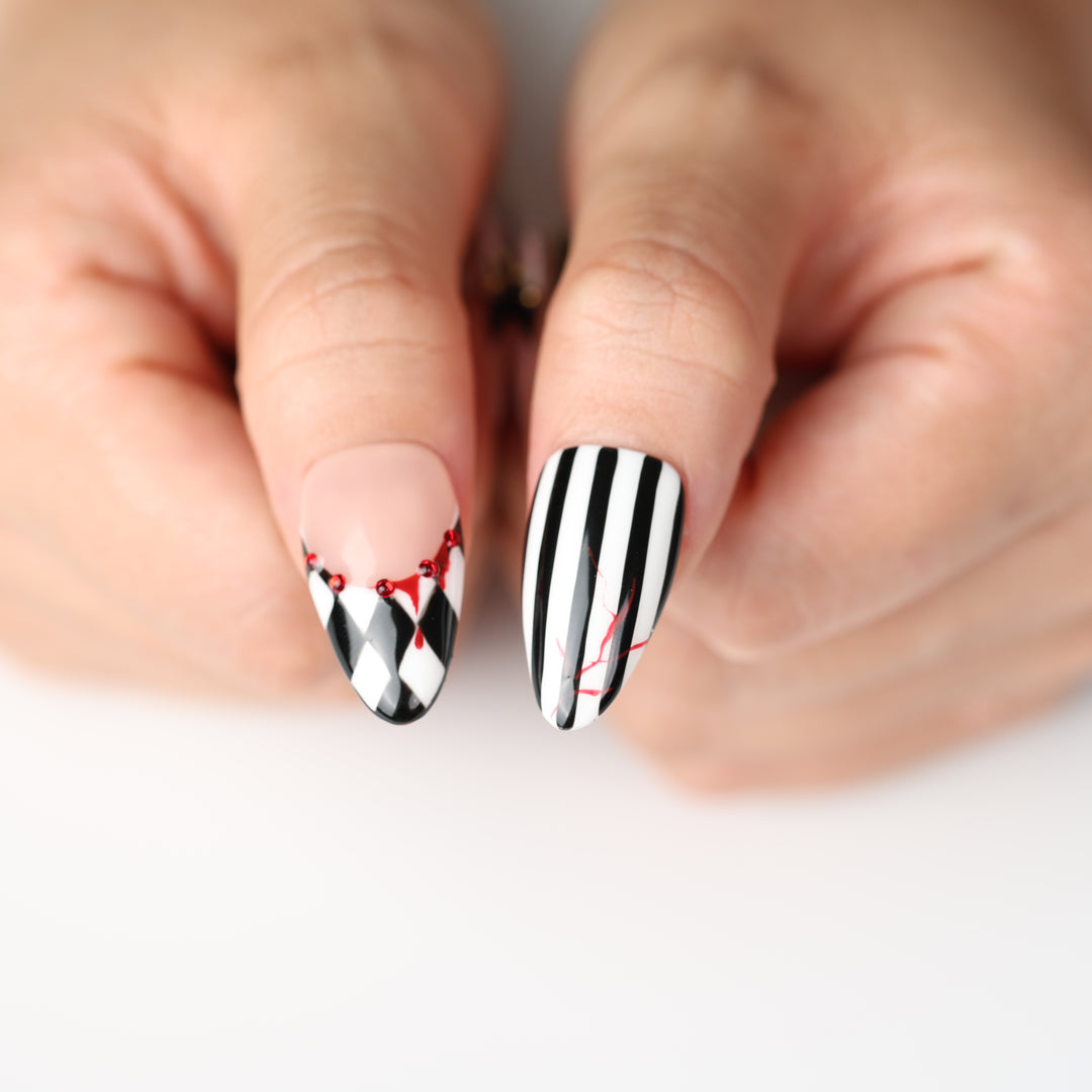 Midnight Marionette press on nails with black-and-white harlequin stripes, red drips, and gothic Halloween flair