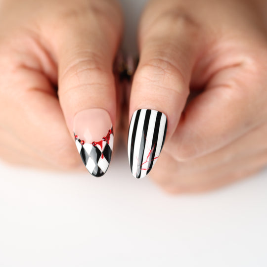 Midnight Marionette press on nails with black-and-white harlequin stripes, red drips, and gothic Halloween flair