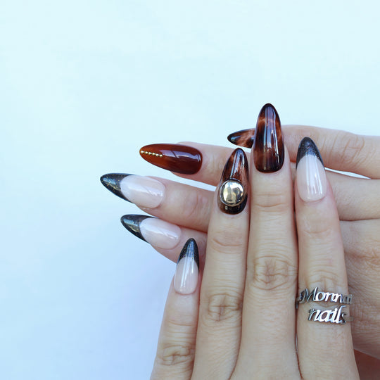 Molten Caramel press-on nails worn on hands, with espresso cat-eye shimmer, nude bases, and dark glitter French tips.
