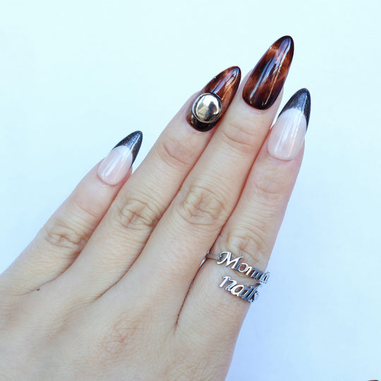 Molten Caramel press-on nails worn on hand, with espresso cat-eye shimmer, nude bases, dark French tips, and a silver dome stud.