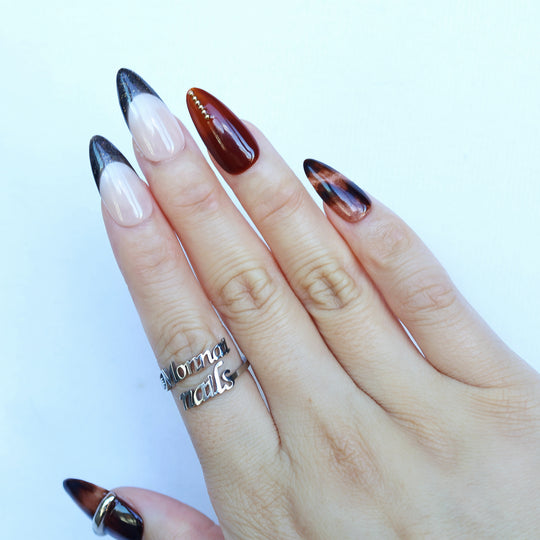Molten Caramel press-on nails on hand, nude and espresso cat-eye tips with glossy metallic accents