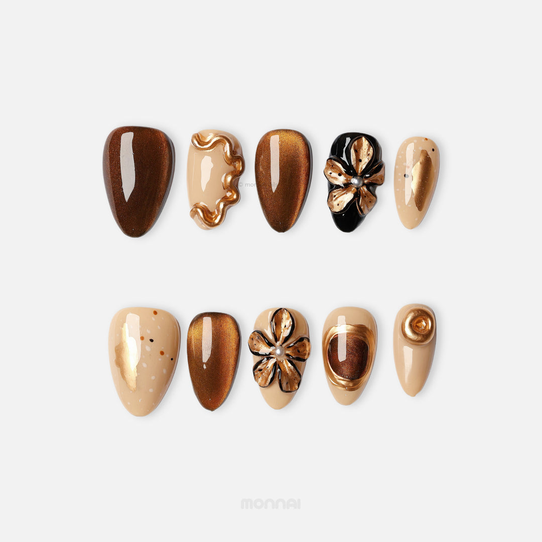 Molten Gold press-on nails laid out in brown and gold cat-eye shimmer with sculpted floral metallic accents.