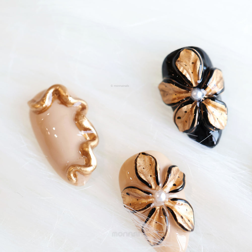 Molten Gold press-on nails shown in close-up, with brown and gold cat-eye shimmer and sculpted floral details