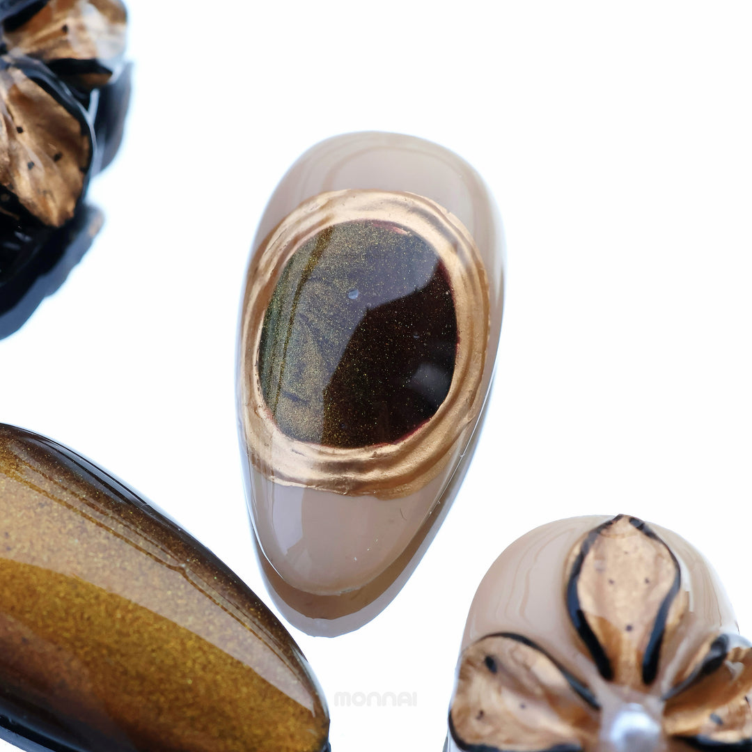 Molten Gold press-on nails in close-up with brown and gold cat-eye shimmer and glossy floral accents