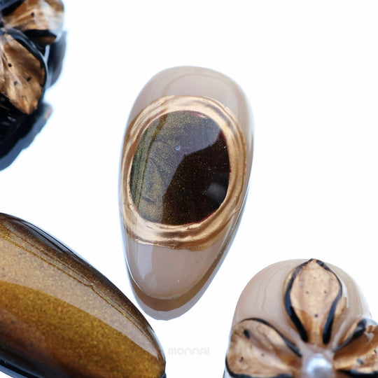 Molten Gold press-on nails in close-up with brown and gold cat-eye shimmer and glossy floral accents