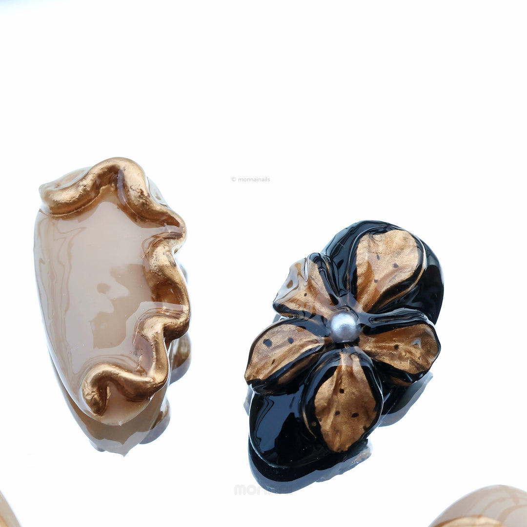Molten Gold press-on nails shown in close-up, with brown and gold cat-eye shimmer and glossy floral accents.