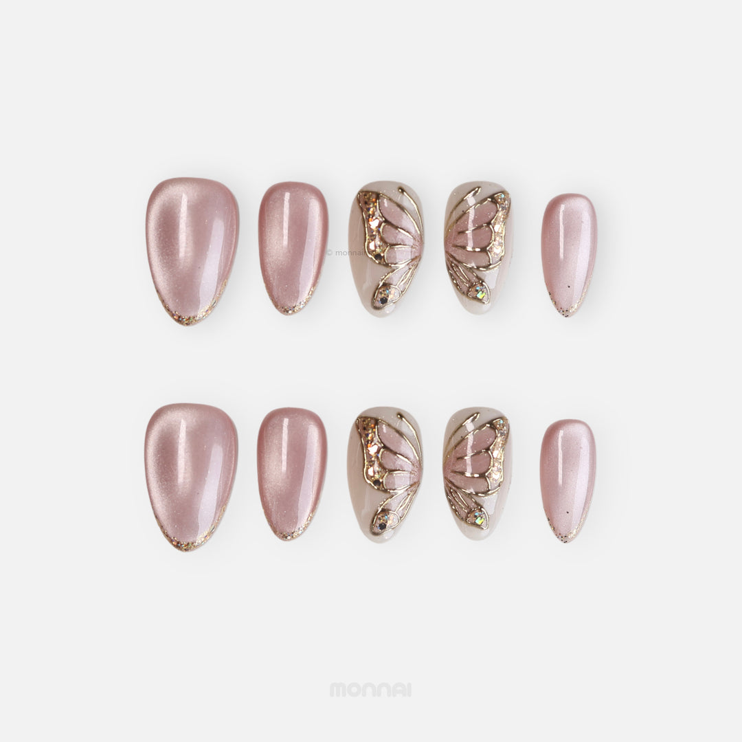 Moonlit Butterfly press-on nails in soft pink fairycore style with gold chrome butterfly wings and glitter accents, laid out in two rows.