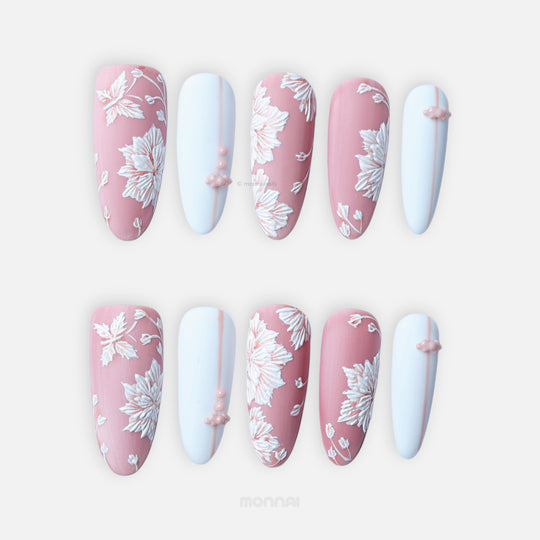 Morning Dew press-on nails laid out in matte pink and pale blue with white floral details and bead accents