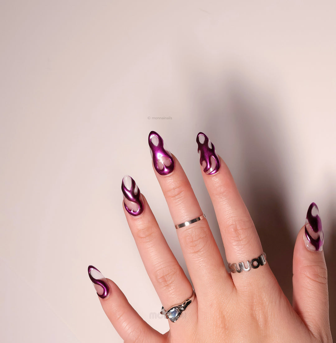 Mystic Flow press-on nails worn on hand, metallic purple chrome swirls with sheer negative space hearts