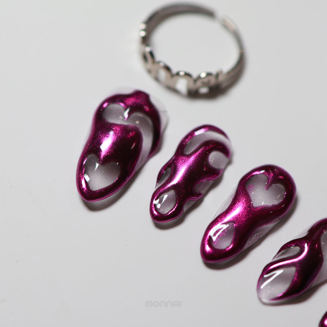 Mystic Flow press-on nails laid out, with metallic purple chrome swirls and heart motifs on a sheer base.