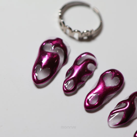 Mystic Flow press-on nails laid out, with metallic purple chrome swirls and heart motifs on a sheer base.