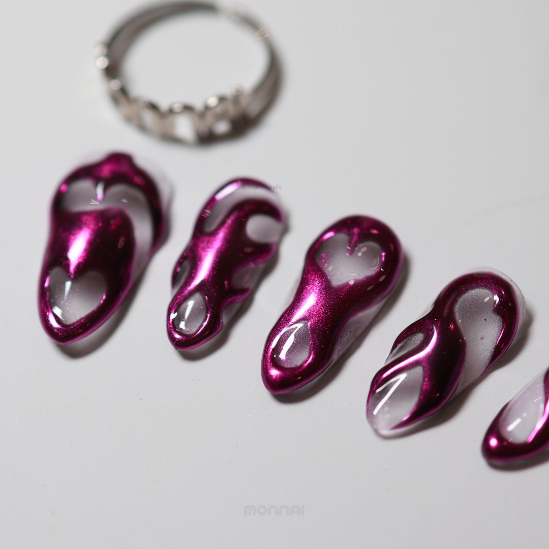 Mystic Flow press-on nails laid out, showing metallic purple chrome 3D swirls with heart-shaped negative spaces.