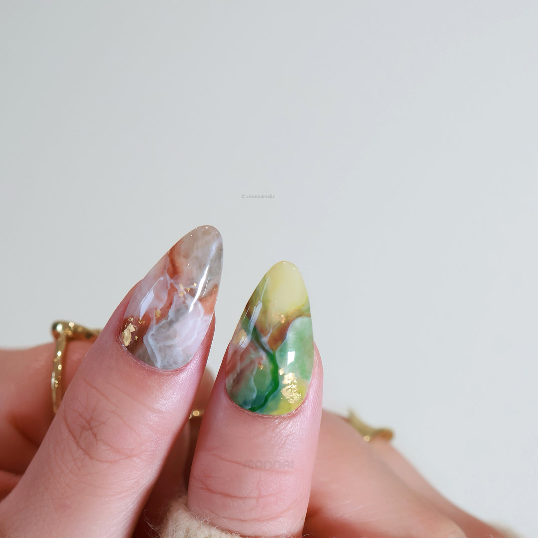 Mystic Marble press-on nails worn on hand, with dreamy watercolor marble swirls and gold foil flakes.