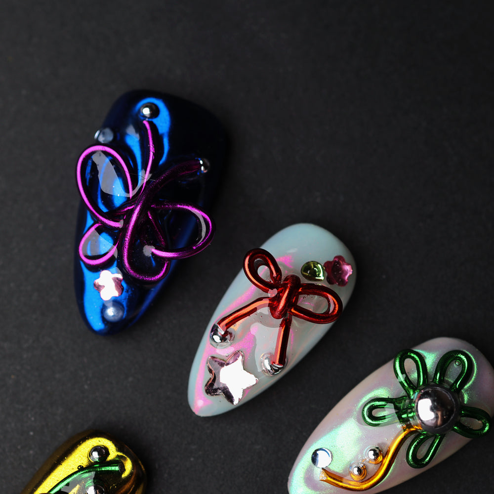 Neon Knots press-on nails laid out in close-up, with blue, white, and iridescent Y2K butterfly and bow accents.