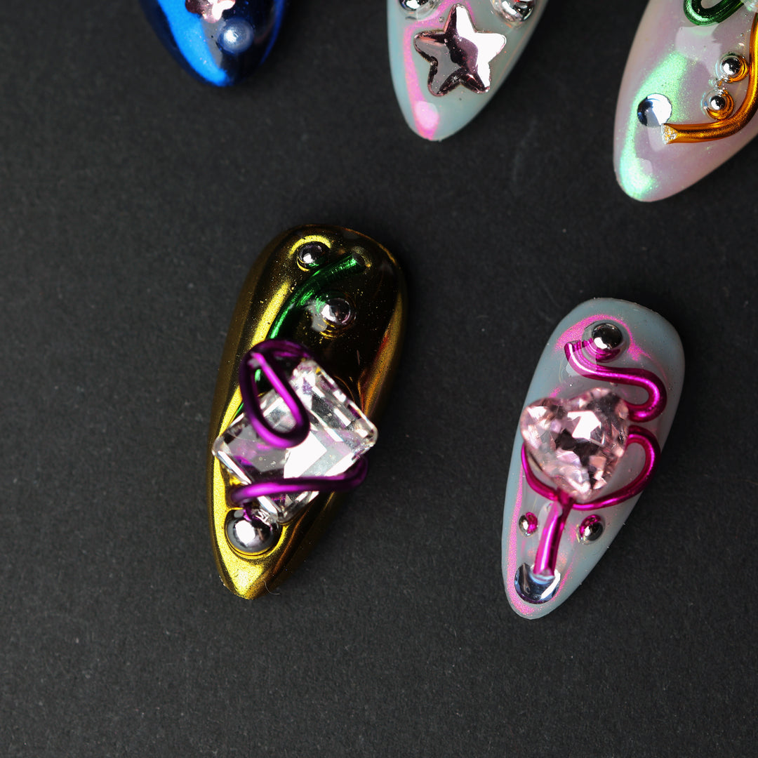 Neon Knots press-on nails in close-up, showing Y2K-inspired chrome gradients with crystal accents and metallic wire details.