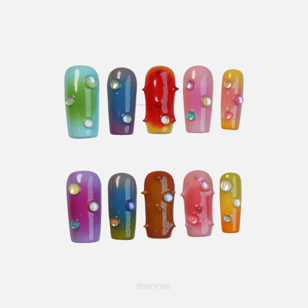 Neon Studs press-on nails laid out in close-up, with mismatched aura gradient colors, 3D studs, and iridescent bead accents.