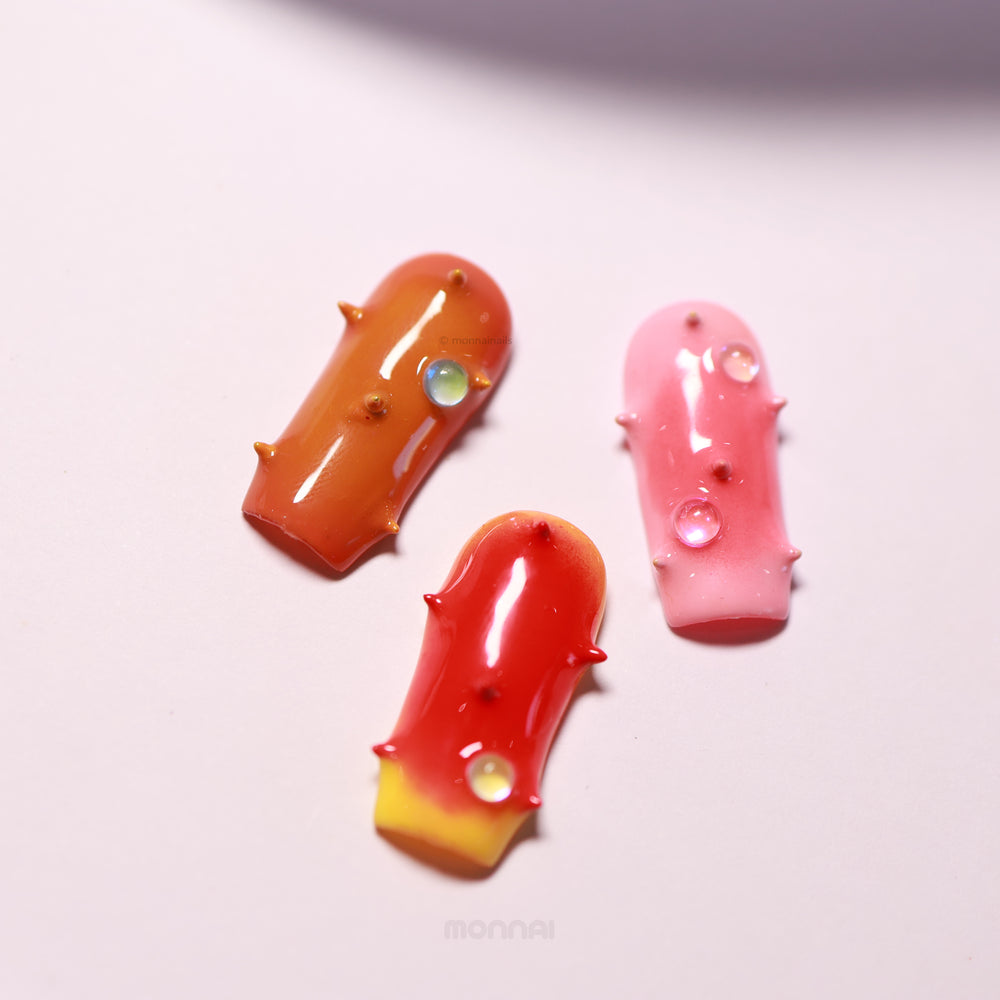 Neon Studs press-on nails in orange, pink, and red with 3D studs and iridescent bead accents