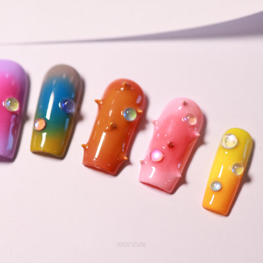 Neon Studs press-on nails laid out in close-up, featuring mismatched aura gradients, 3D studs, and iridescent bead accents.