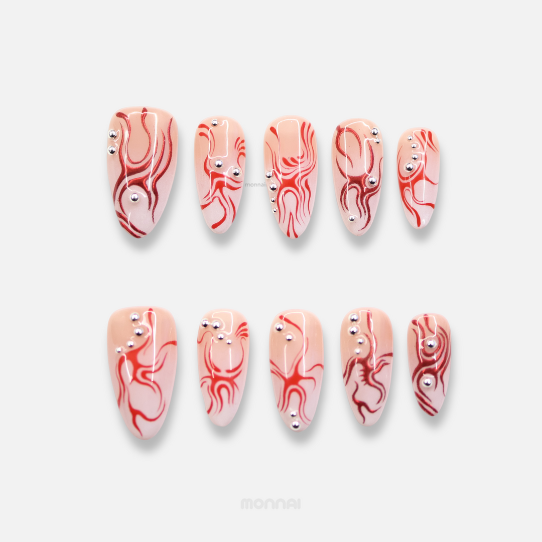 Neural Flux press-on nails laid out with red swirls, silver beads, and a sheer nude base