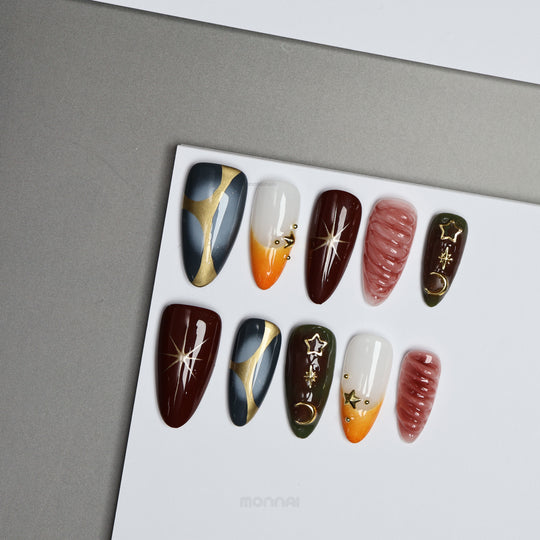 Nocturne press-on nails displayed on a card, featuring moody burgundy, slate blue, olive, nude, and gold star and moon details.