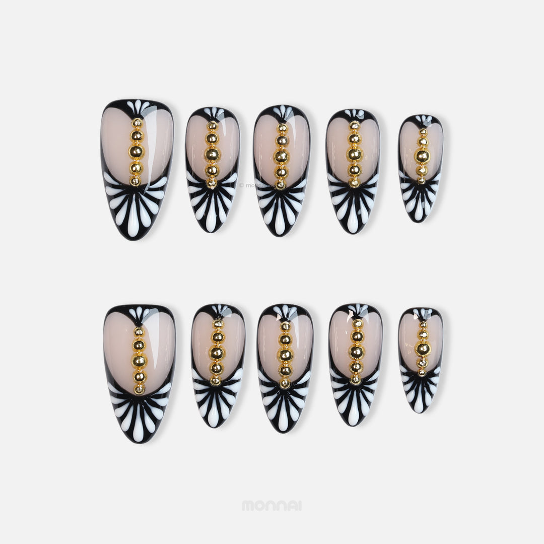 Noir Chic press-on nails with nude center, black-and-white fan pattern, and gold bead row, shown laid out in close-up.
