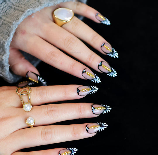 Noir Chic press-on nails on hands, nude base with black fan pattern and gold bead accents