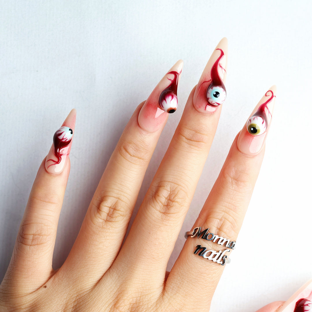 O-O press-on nails with surreal 3D eyeball charms and blood-red drip details worn on hand