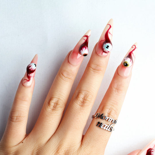 O-O press-on nails with surreal 3D eyeball charms and blood-red drip details worn on hand