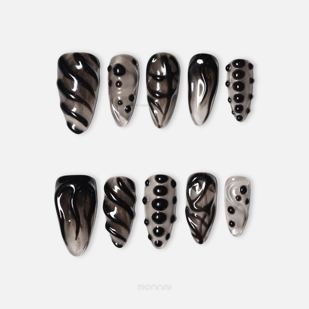 Obsidian Mist press-on nails in close-up, sheer nude with abstract black detailing, raised gel lines, and glossy bead accents.
