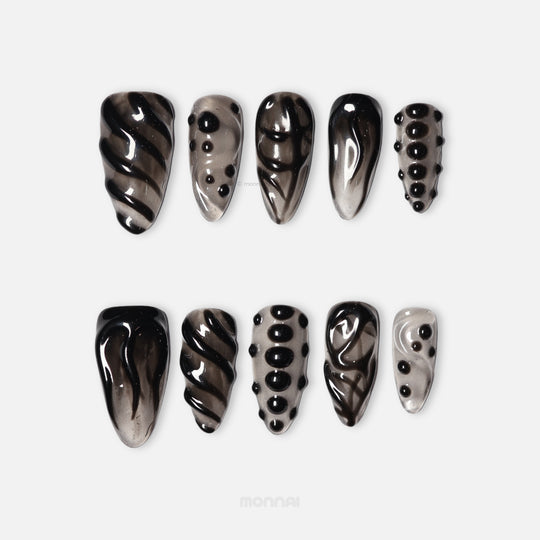 Obsidian Mist press-on nails in close-up, sheer nude with abstract black detailing, raised gel lines, and glossy bead accents.