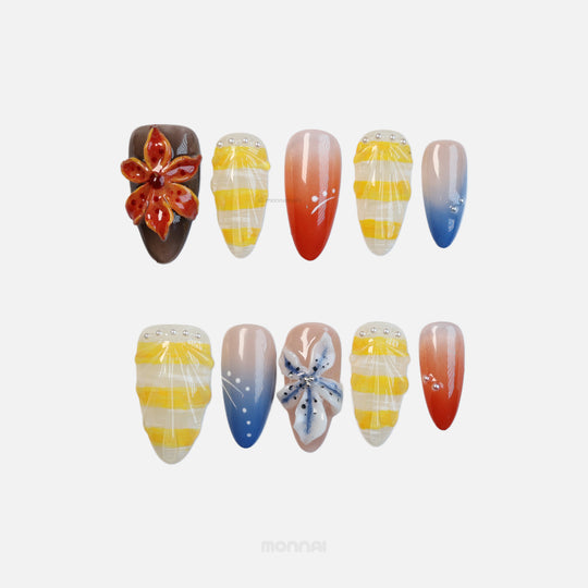 Ocean Bloom press-on nails laid out with tropical florals, glossy yellow stripes, blue-to-red gradients, and bead accents