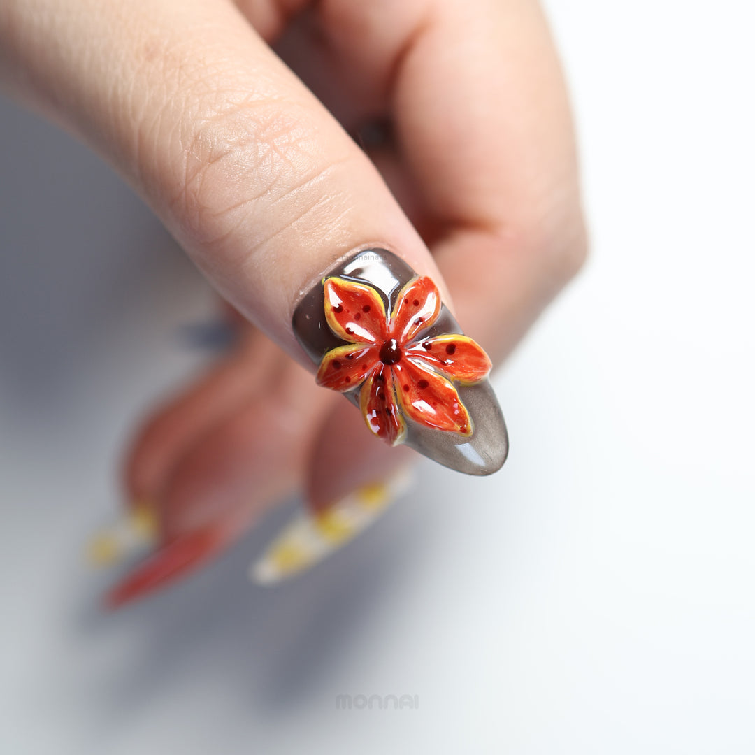 Ocean Bloom press-on nails in close-up, with glossy orange floral design and sheer gray base.