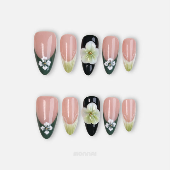 Olive Petal press-on nails laid out, with sheer nude, green French tips, white flowers, and black accent bloom.