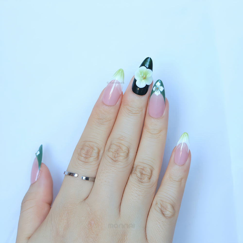 Olive Petal press-on nails worn on hand, with green French tips, pink bases, and floral accents.