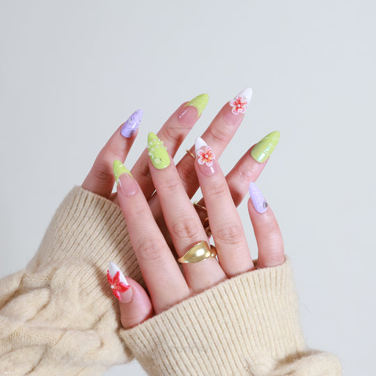 Orchid Glow press-on nails worn on hands, showing hyper-pop green and lavender floral accents with pearls.